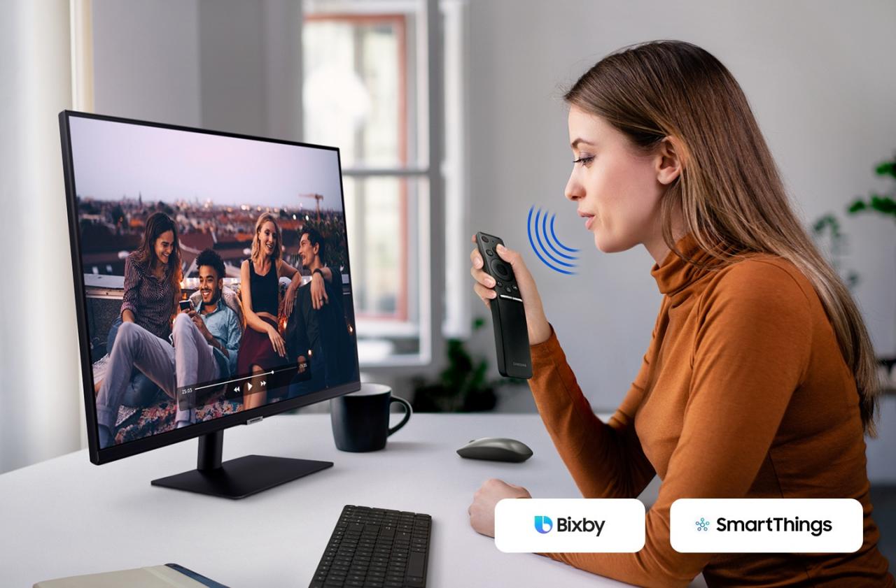 Một phụ nữ nói với màn hình. Và một đoạn video được phát trên đó. Biểu tượng Bixby và SmartThings nằm ở góc bên phải.